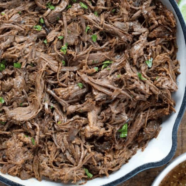 beef in a pan with salsa and lime on side