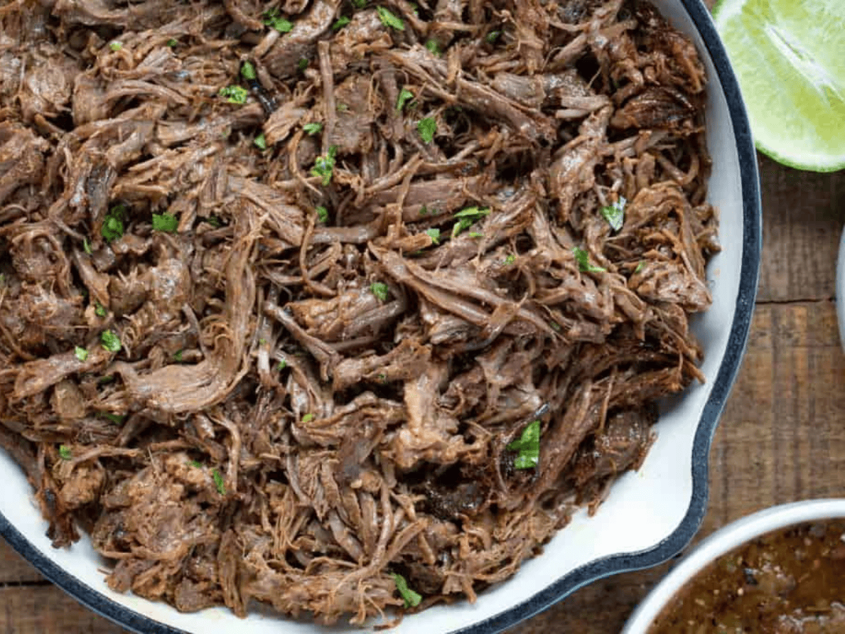 meat in pan with salsa and lime on the side 