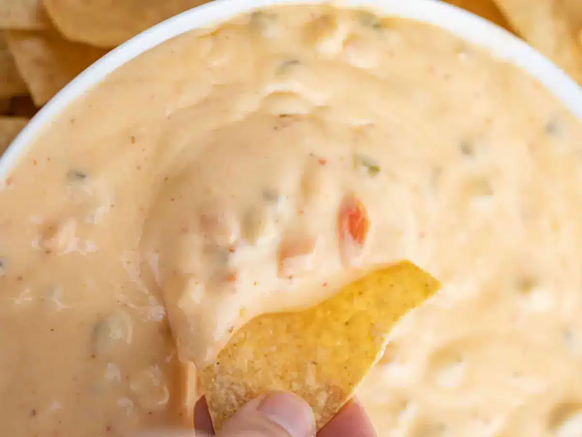 A chip being dipped in queso