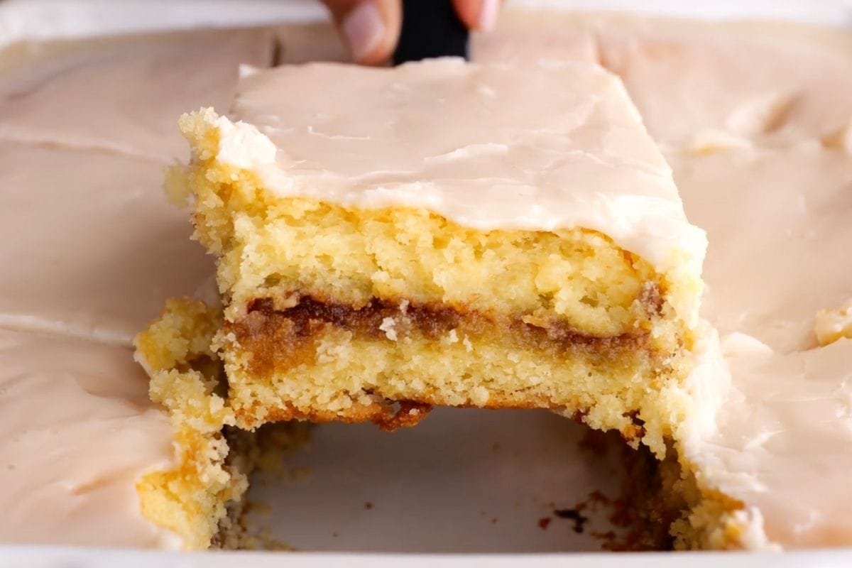 Honey Bun Cake slice being lifted from baking dish with spatula