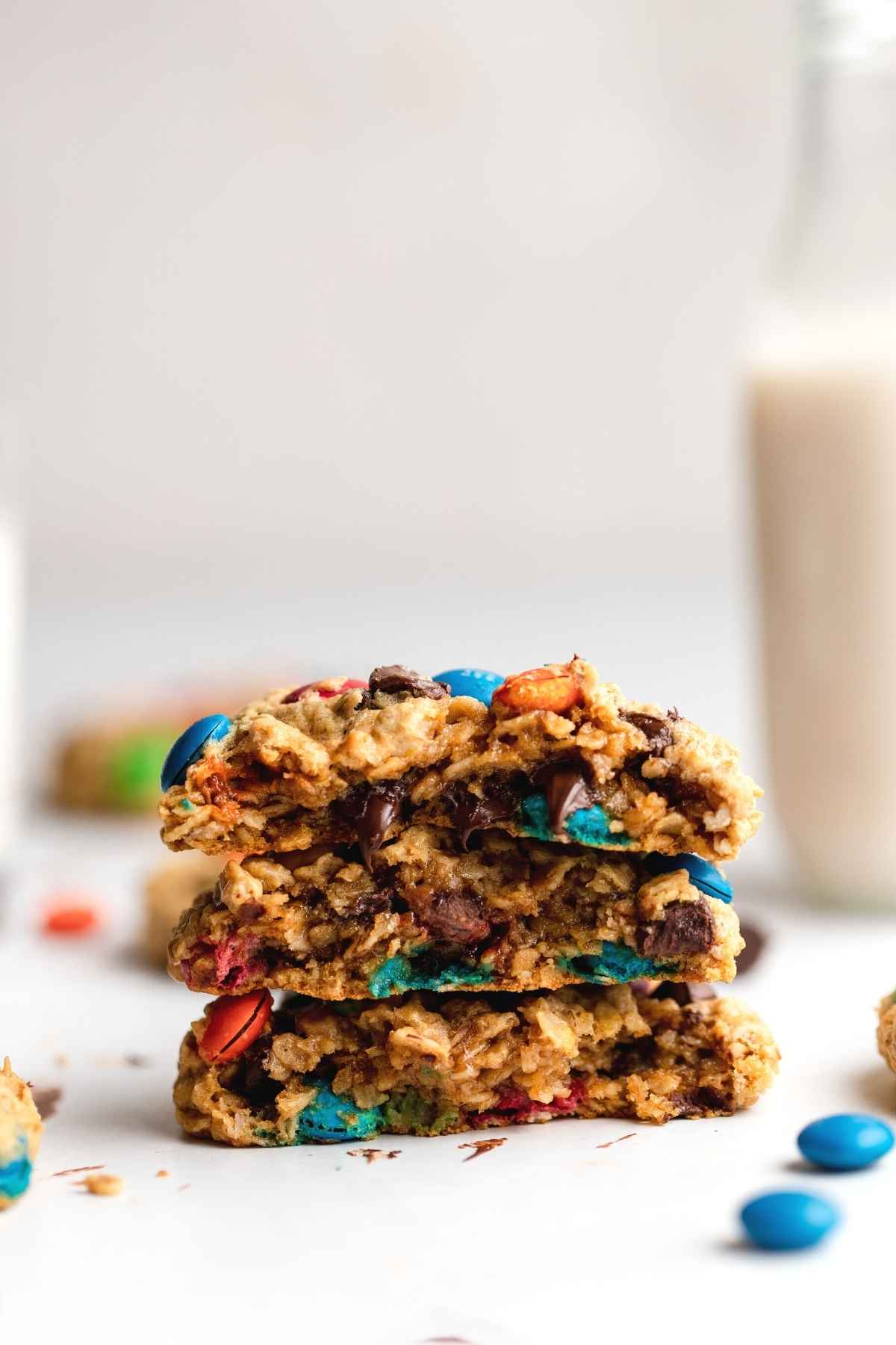 Monster Cookies stacked on table with glass of milk