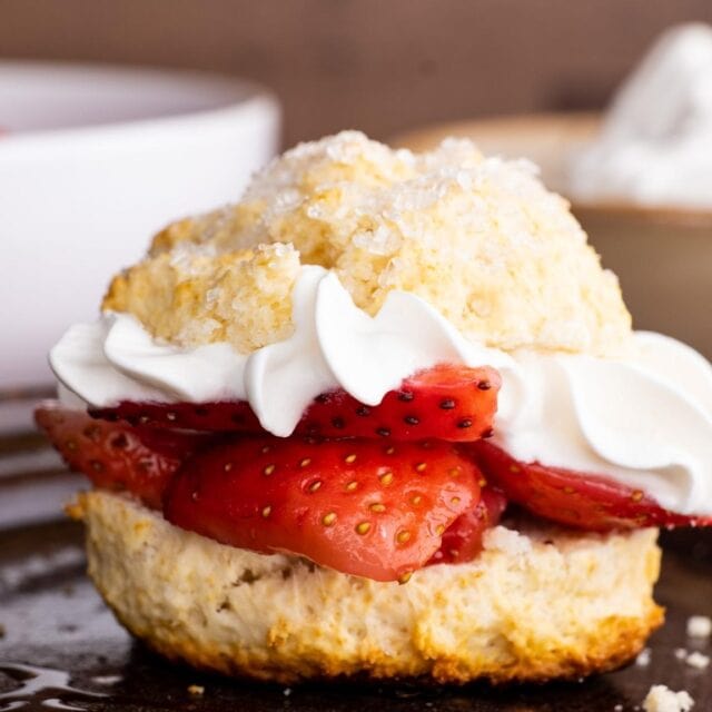 Strawberries and whipped cream layered in a biscuit on plate