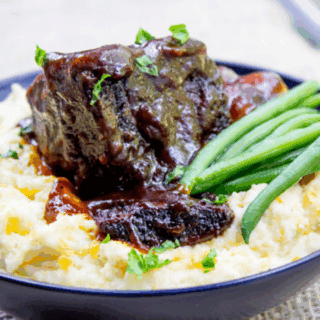 Short ribs in blue bowl over veggies with green beans