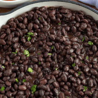 Cooked black beans in a pot with seasonings and cooking liquid