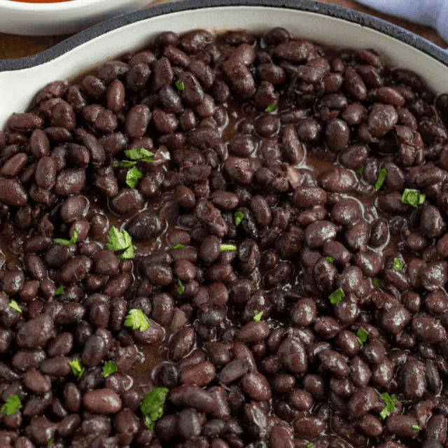 Cooked black beans in a pot with seasonings and cooking liquid