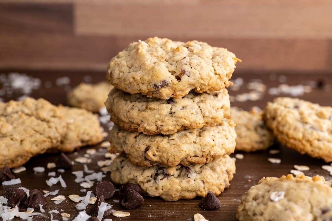 Cowboy Cookies stacked on board with coconut flakes and chocolate chips