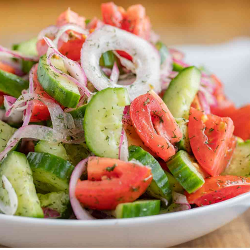 Sliced cucumbers, tomato, onion and herb garnish.