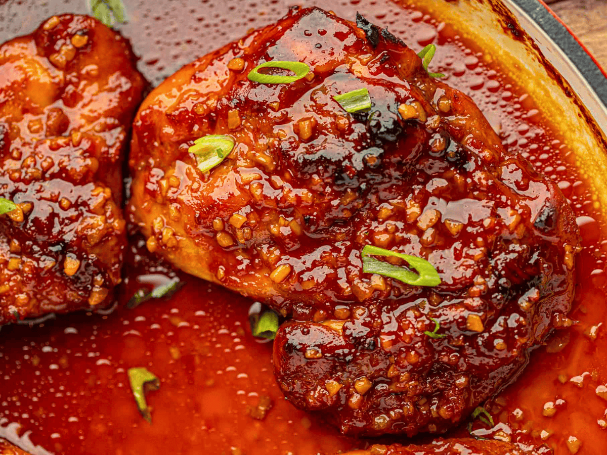 close up of spicy caramelized chicken in skillet with green garnish