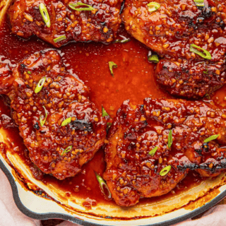 spicy caramelized chicken in skillet with green garnish