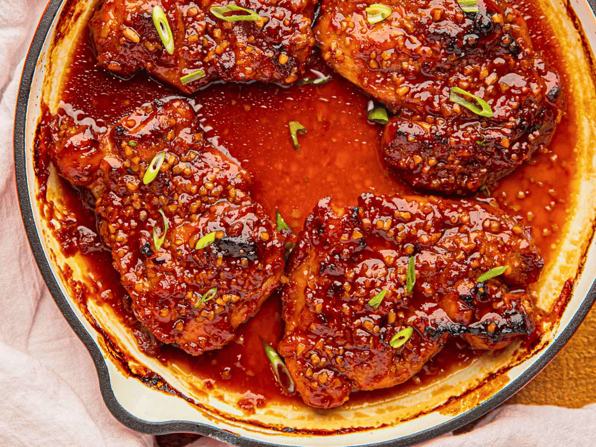 spicy caramelized chicken in skillet with green garnish