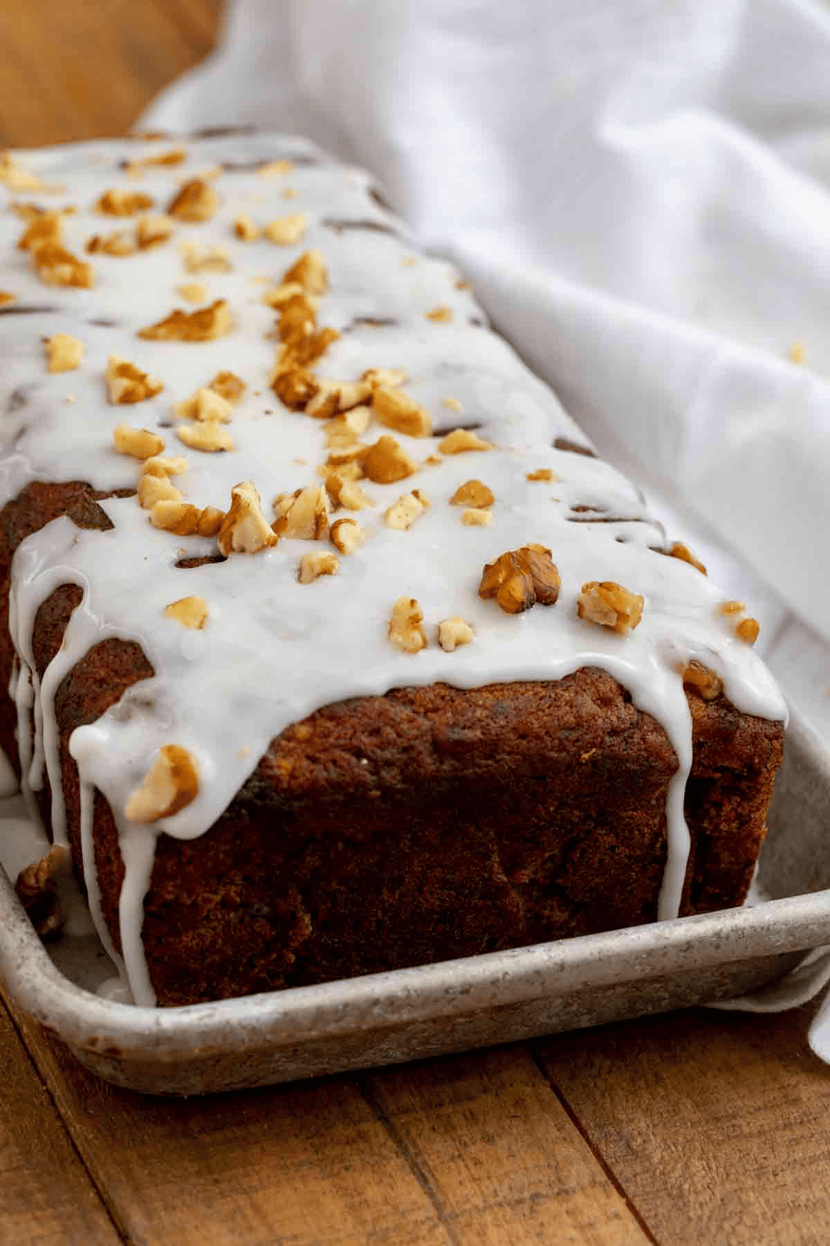 Sweet bread loaf with glaze and nut topping shown from the side