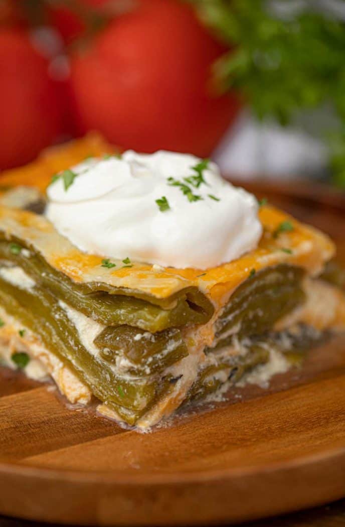 Slice of Chile Relleno Casserole with Green Chiles, Cheddar Cheese and Sour Cream on Wooden Plate