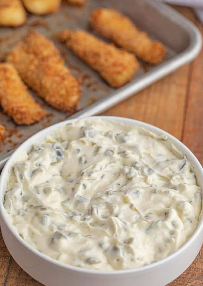 Tartar Sauce in white bowl with fish sticks in background