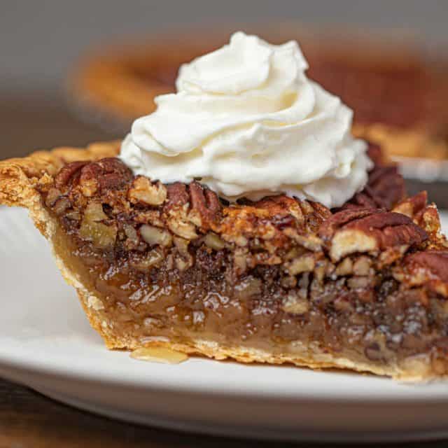 slice of sweet, nutty, dessert on top of crust with a dollop of cream