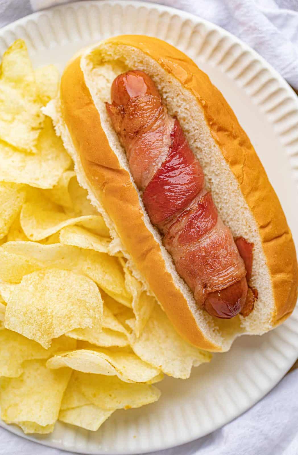 Hot dog on a serving plate with chips