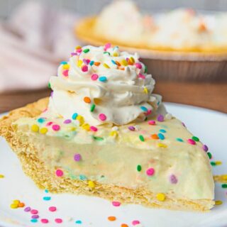 Pie slice topped with whipped cream and sprinkles on plate.