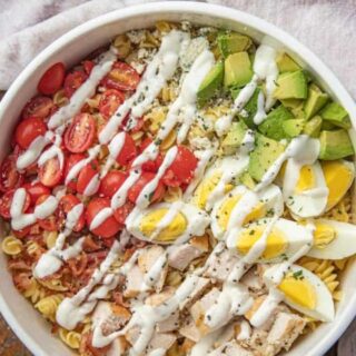 Salad with pasta, chicken eggs, avocado, bacon and dressing