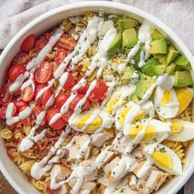 Salad with pasta, chicken eggs, avocado, bacon and dressing