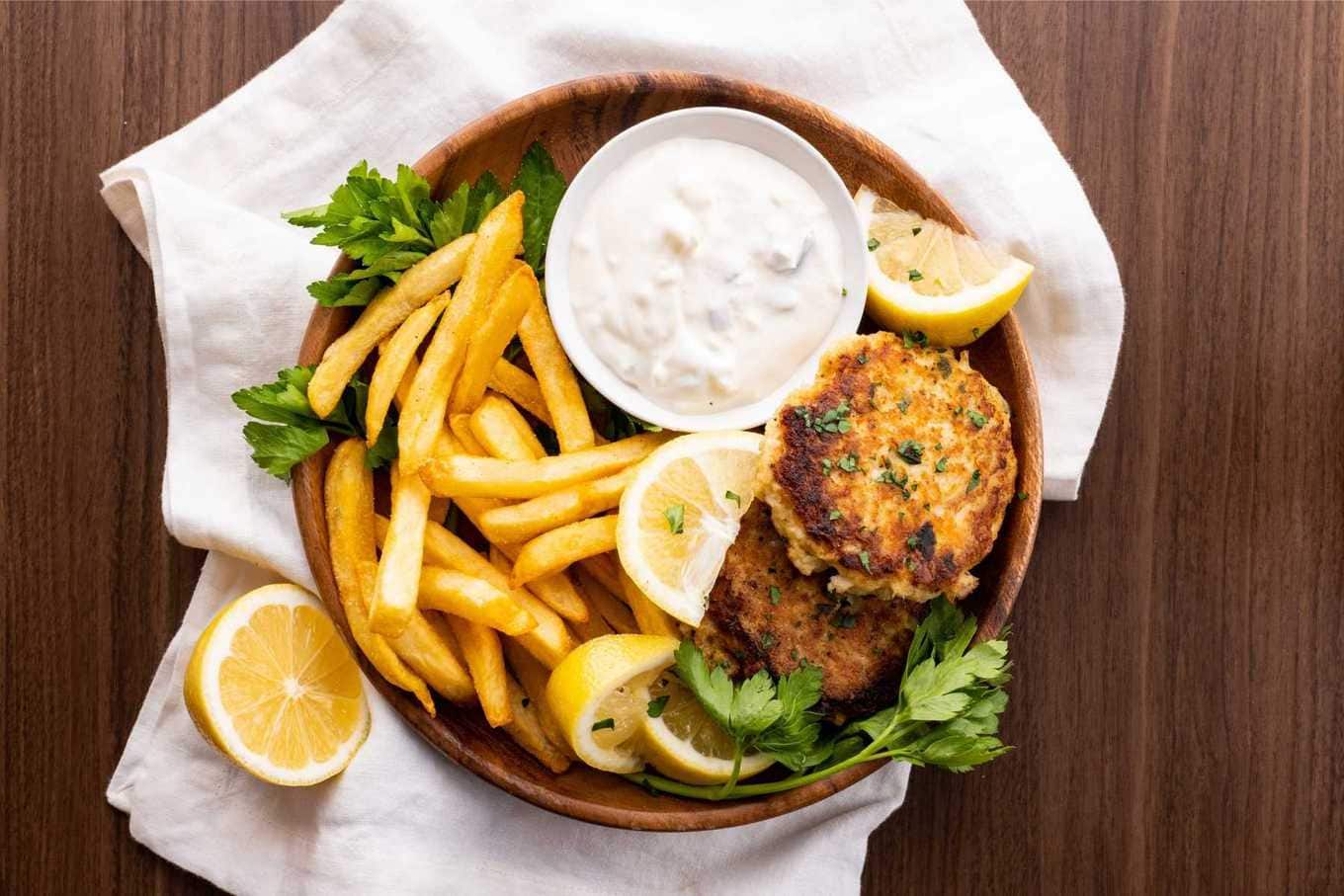 Crab Cakes on plate with lemon wedge, tartar sauce, and french fries