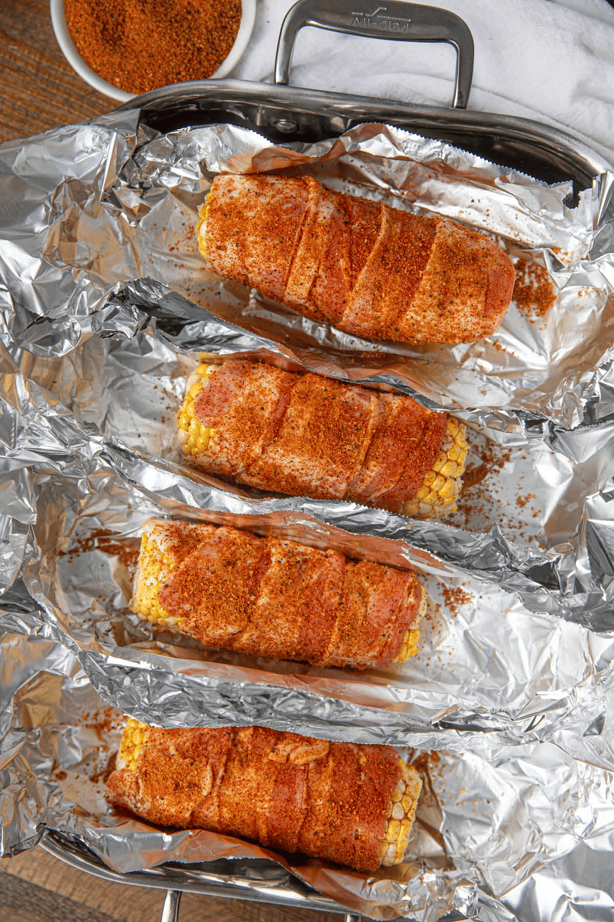 Raw seasoned bacon wrapped around corn