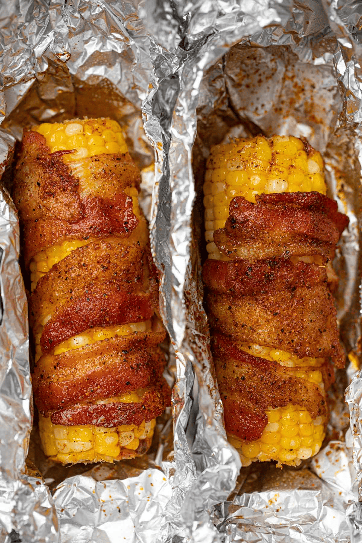 Two pieces of corn wrapped in bacon