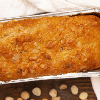bread in a loaf pan after baking with nut on table