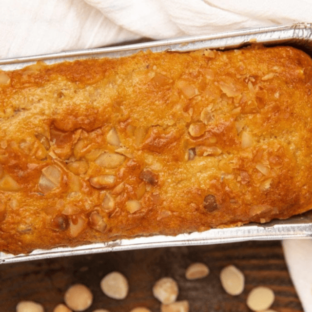 bread in a loaf pan after baking with nut on table