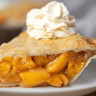 Peach pie topped with a dollop of whipped cream for garnish
