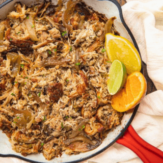 chicken in a red skillet with lemons and limes