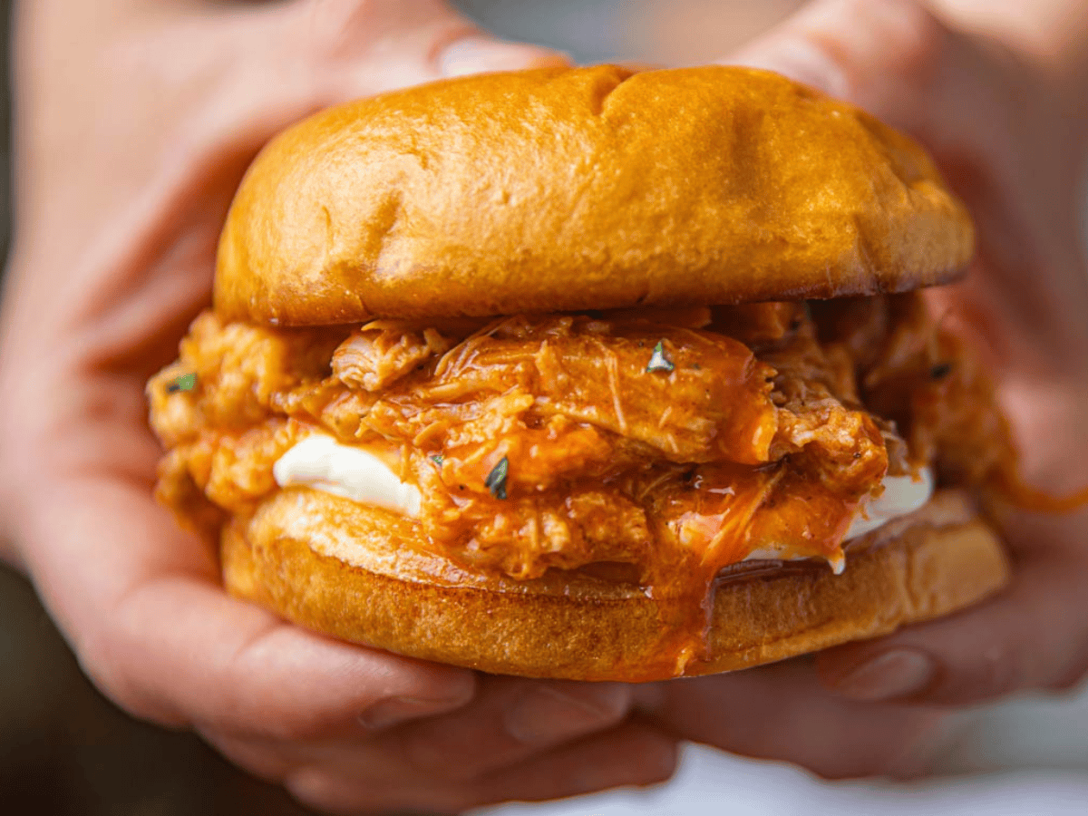 Closeup of poultry in between 2 slices of bread