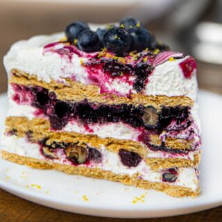 Slice of dessert with layers of whipped cream, berries and graham crackers