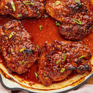Chicken submerged in sauce in white pan with chives
