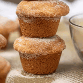 muffins stacked beside a bowl of cinnamon sugar