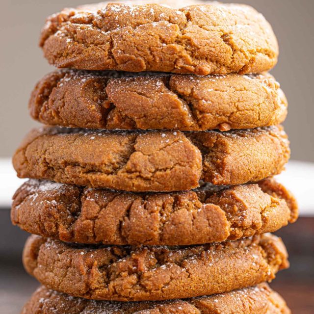 soft, spiced circular treat with dusted sugar on top stacked on one another