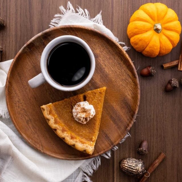 Pumpkin Pie slice on plate with coffee
