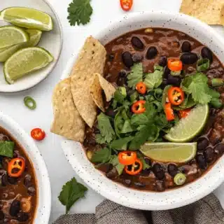 bowl of bean soup with cilantro limes and chips