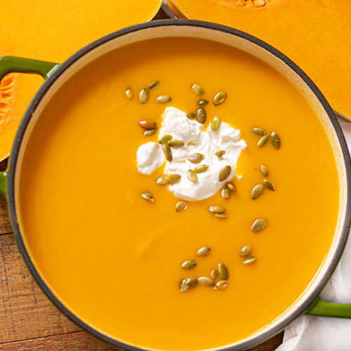 Homemade soup in a pot topped with seeds and cream
