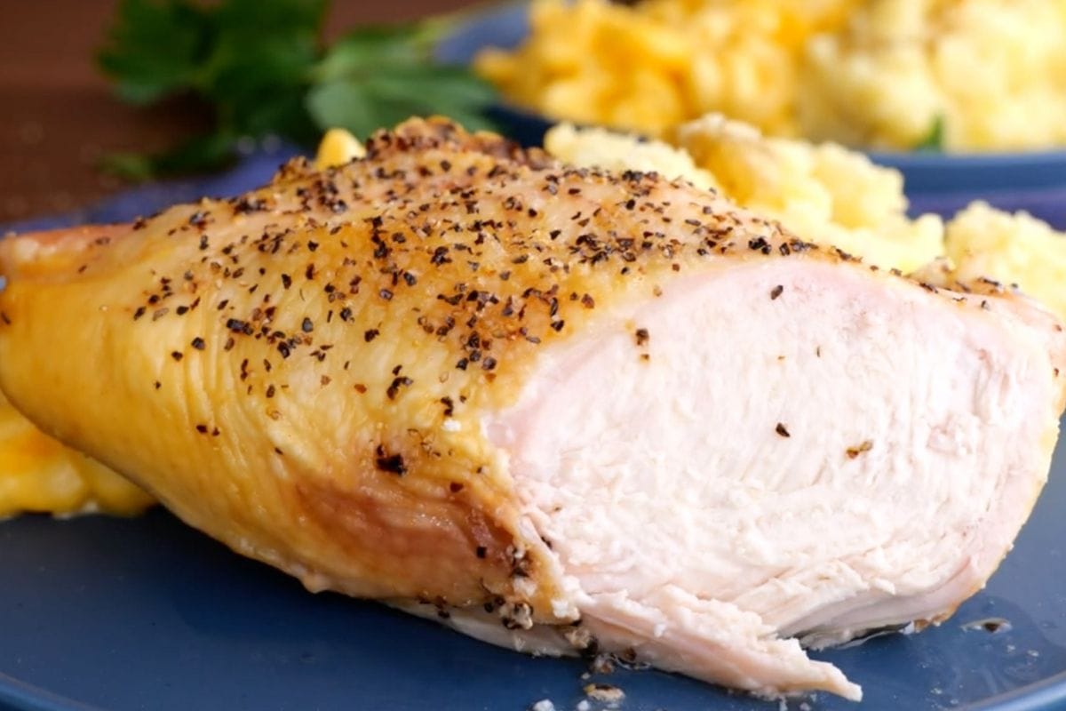 Oven Baked Split Chicken Breasts sliced on plate with sides