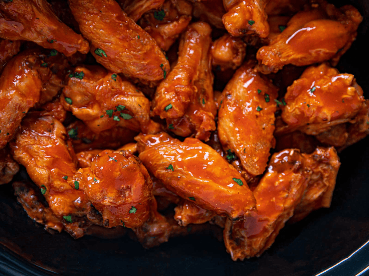 Close-up of cooked buffalo wings in a black crockpot