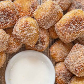 Warm, golden pieces coated with sweet crystals on a platter with white dipping sauce in the middle