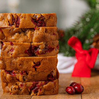 Cut up slices of pumpkin bread with cranberries in it stacked on top of eachother