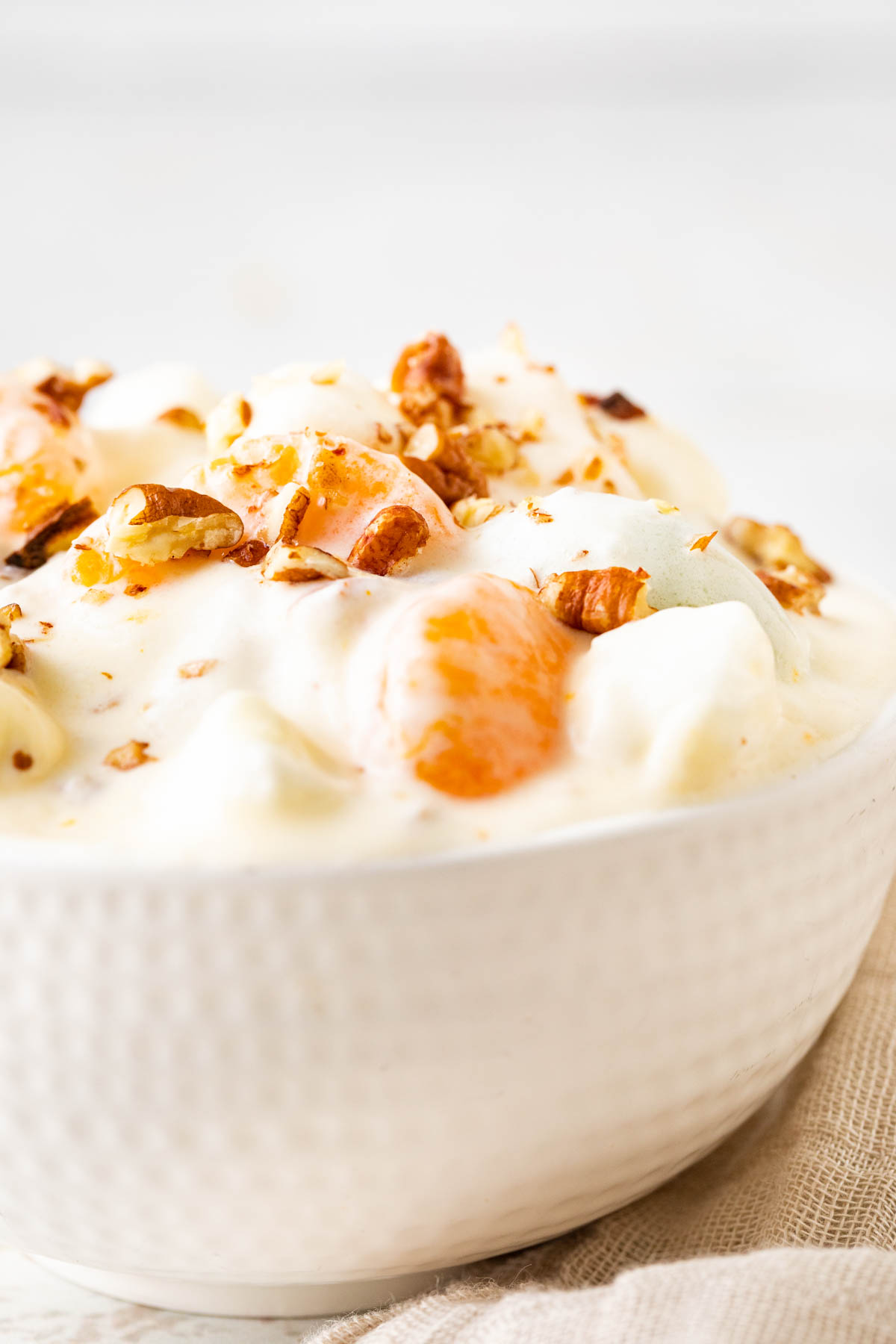 Overnight Fruit Salad with whipped cream and nuts in bowl