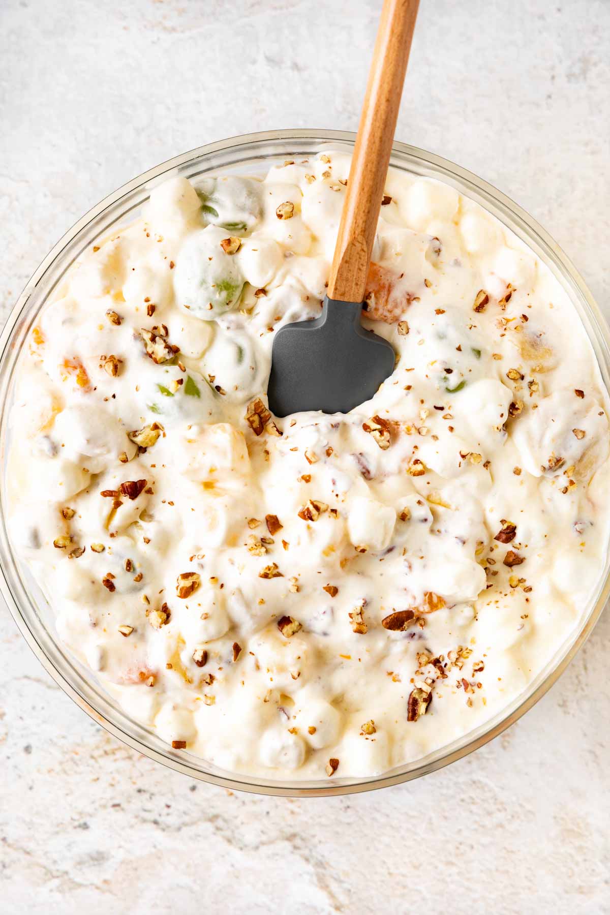 Overnight Fruit Salad with whipped cream and nuts in bowl