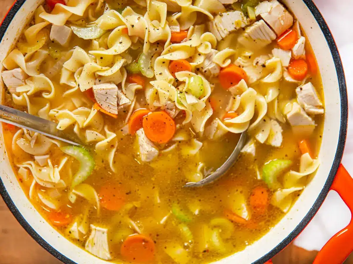 Cooked broth, veggies, and seasoning in pot with spoon inside