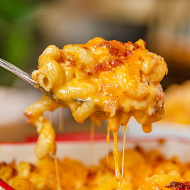 Mac and Cheese with bacon on a spoon over baking dish