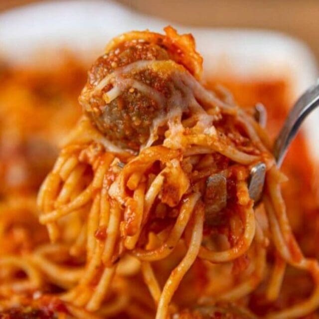 Scooping spaghetti and meatball out of a dish