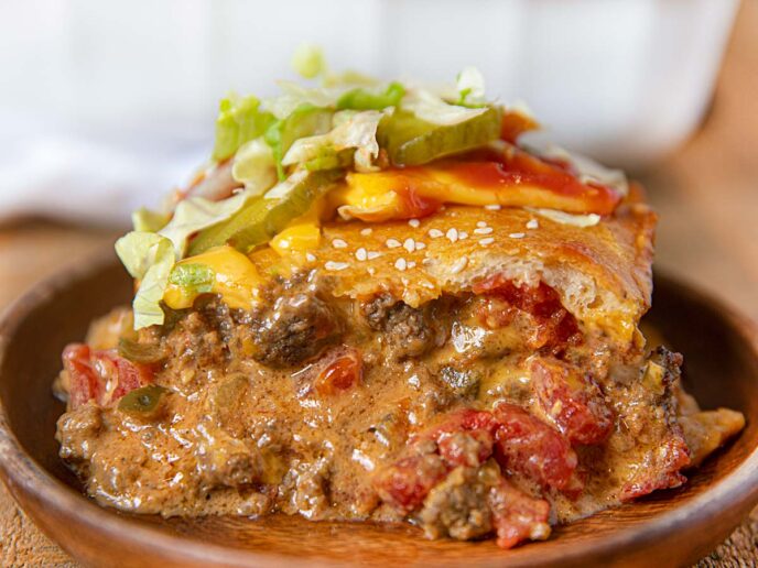 Cheeseburger Casserole topped with bread and sesame seeds on wooden plate