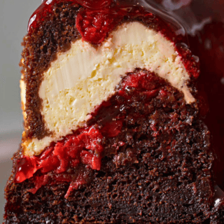 a slice of chocolate cake with cherries and cheesecake with glaze on top