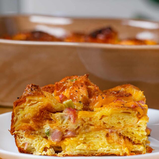 Slice of Ham Cheese and Egg Croissant Casserole on small white plate