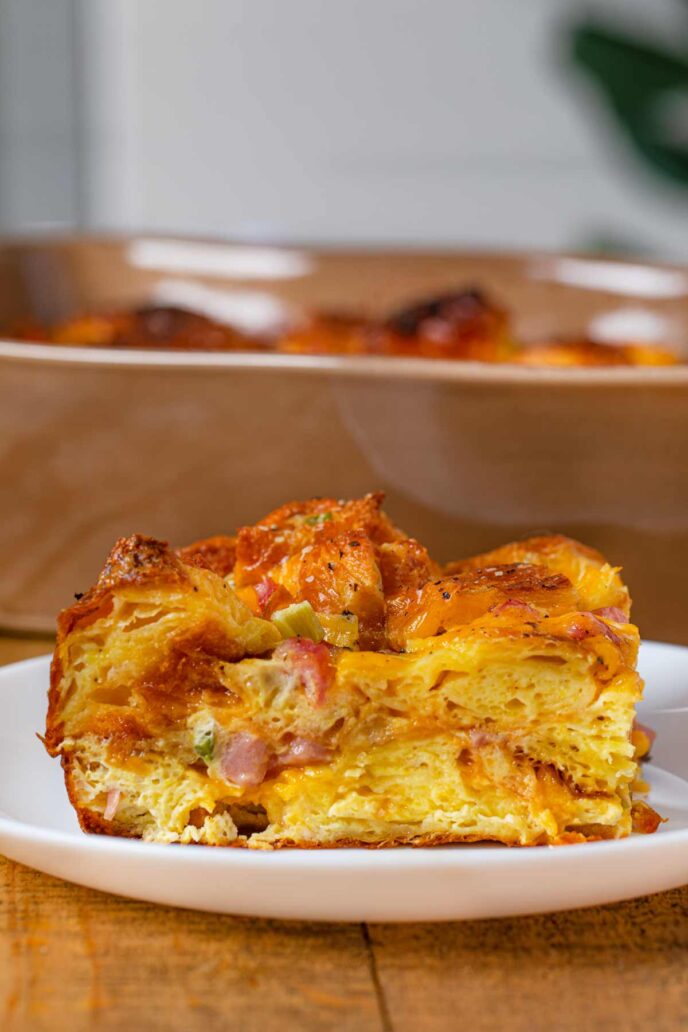 Slice of Ham Cheese and Egg Croissant Casserole on small white plate